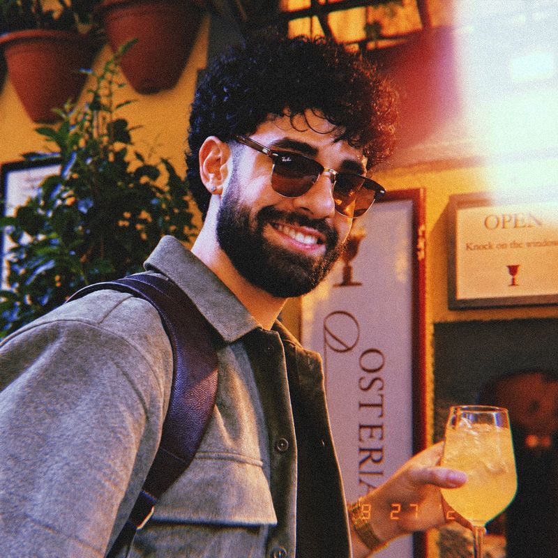 Tetra in sunglasses, smiling and raising a glass outside an osteria